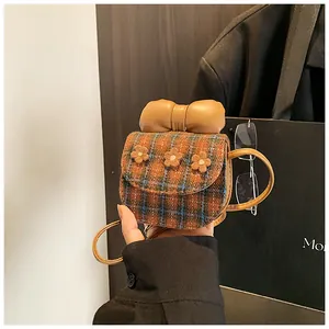Detail of mini plaid crossbody bag with leather bow and three 3D flower decorations