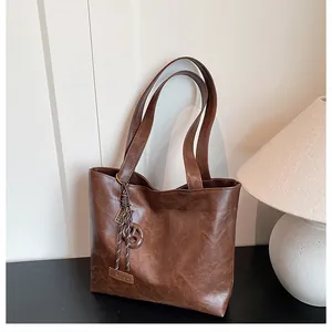 Détail du sac cabas vintage en similicuir marron avec étiquette et pendentif décoratif