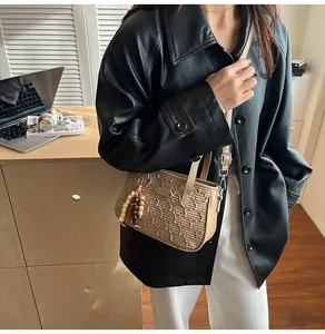 Détail du sac à bandoulière matelassé beige avec texture ondulée et breloque
