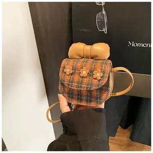 Detail of mini plaid crossbody bag featuring 3D flowers and a prominent yellow leather bow