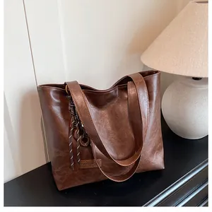 Détail d'un grand sac cabas marron en cuir avec étiquette mode et bijou de sac