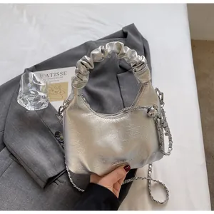 Detail of silver pleated handle handbag with metallic texture and chain strap