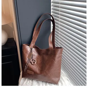 Détail du cabas marron à texture vintage avec étiquette en cuir et pendentif à nœud