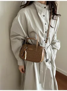 Détail du sac à main en cuir marron gaufré avec pompon perlé et garnitures argentées