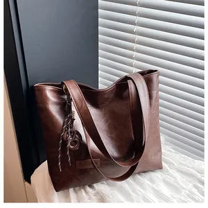 Détail de la texture en similicuir marron foncé et du logo sur le sac fourre-tout