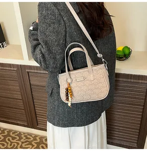 Détail du sac beige texturé avec pendentif en perles de bois et fermoir métallique