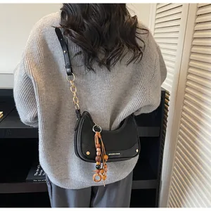 Detail of black half-moon chain bag worn by model showing its actual size and stylish fit