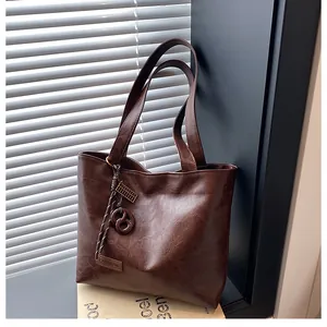 Détail du sac cabas en similicuir marron avec grain naturel et pendentif en métal gravé