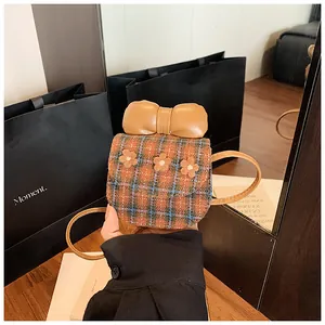 Detail showing mini plaid crossbody bag with decorative floral pattern and large bow