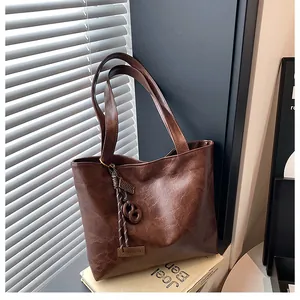 Gros plan sur la texture du sac cabas marron foncé avec détail de pampille tissée
