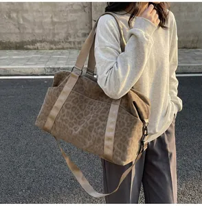 Detail of leopard print travel tote showing side pocket and durable nylon straps
