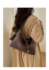 Detailed side view of deep coffee pebble leather tote bag worn with a beige trench coat