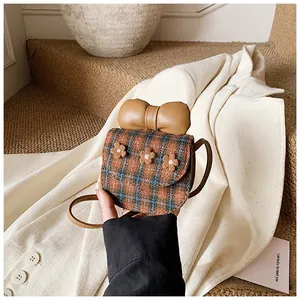Close-up of cute plaid crossbody bag with khaki leather bow and plush floral details