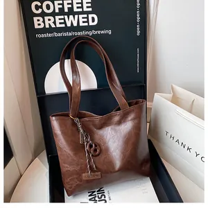 Détail d'un sac cabas en cuir marron foncé montrant la texture et l'étiquette argentée