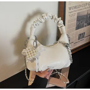 Detail of cream white mini crossbody bag with pleated handle, pearl heart and lace bow