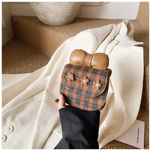 Close-up of mini plaid crossbody bag with leather bow and plush flower details