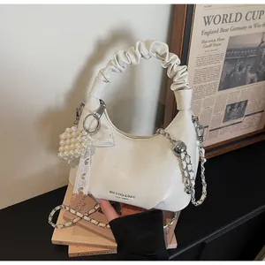 Detail of white moon bag with cloud pleats, pearl heart charm and silver chain strap