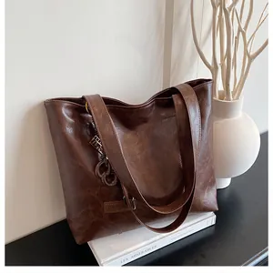 Gros plan du sac cabas en cuir PU marron foncé avec texture vintage et étiquette mode