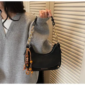 Detail of black leather hobo bag with gold chain strap and vintage beaded charms