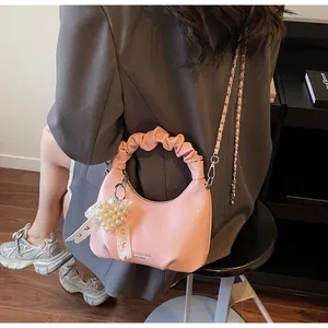 Detail of pink pleated hobo bag with silver chain strap and pearl heart charm