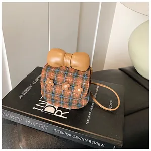 Detailed close-up of plaid mini bag featuring a large leather bow and plush flower accents