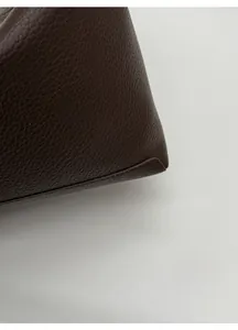 Close-up of premium dark brown lychee pattern leather and exquisite stitching on a tote