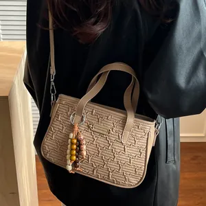 Sac à main tissé beige chic pour femme avec un gland perlé élégant et emblème en métal