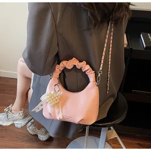 Detailed view of pink pleated handbag with pearl heart charm and silver metal chain strap