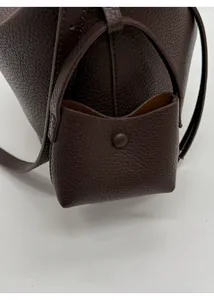 Detail of dark brown pebble leather bucket bag with a matching mini pouch charm attached