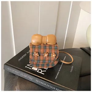 Detail shot of mini plaid crossbody bag with bow and flowers on a vintage book