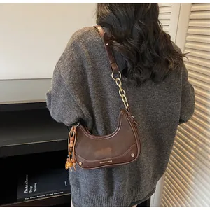 Detail of dark brown crescent hobo bag with chain strap and bead tassel decoration