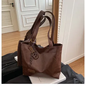 Gros plan sur un sac cabas en similicuir marron foncé avec larges anses et étiquette métal