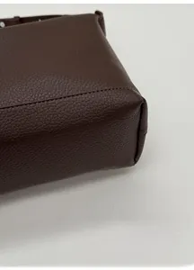 Detailed view of the wide base and grainy leather texture on this stylish shoulder bag