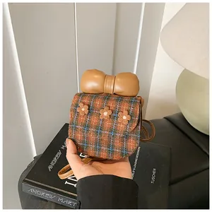 Detailed view of mini tweed plaid bag with 3D plush flowers and large leather bow