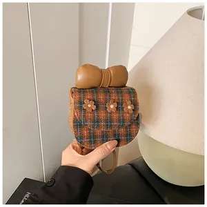 Macro detail of mini checkered bag with plush flower accents and large brown bow handle