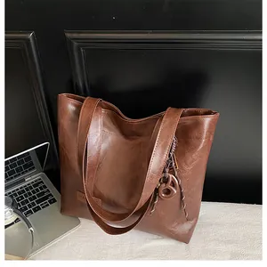 Gros plan d'un cabas en cuir marron texturé avec étiquette mode et pendentif tressé