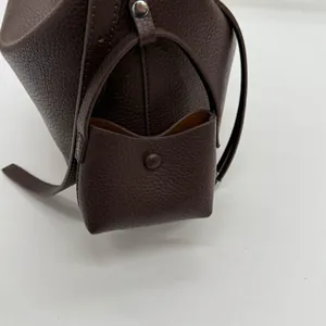 Detailed macro view of litchi grain cowhide texture and small matching pouch attachment
