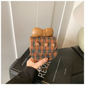 Close-up of brown plaid mini bag with 3D floral accents and oversized bow detail