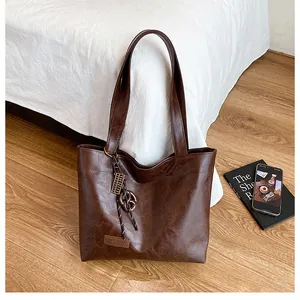 Gros plan d'un cabas en cuir PU marron foncé avec étiquette Fashion et breloque tissée