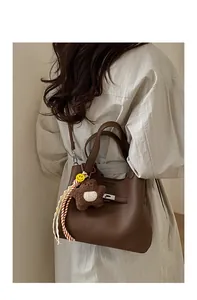 Detail of dark brown lychee grain leather bucket bag with plush star and smiley charm
