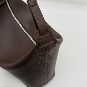 Detail of dark brown lychee grain leather handbag with smooth silver zipper closure
