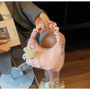 Detail of pink pleated handle handbag featuring a pearl heart charm and lace ribbon