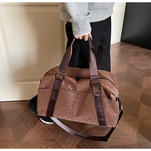 Detail of dark brown leopard print travel bag with adjustable strap and dual handles