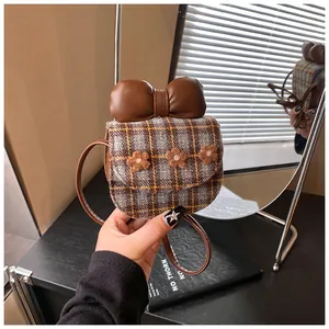 Detail of checkered mini crossbody bag with leather bow and floral accents decoration