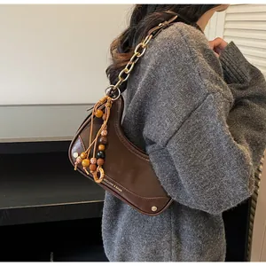 Close-up of dark brown saddle bag with gold chain and colorful beaded tassel detail