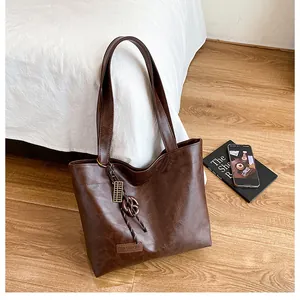 Détail du sac fourre-tout marron foncé avec pendentif créatif et étiquette de mode