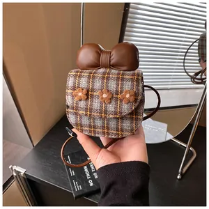 Detailed view of mini plaid crossbody bag with brown leather bow and flower accents