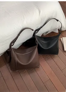 Detail of minimalist leather tote bags in dark brown and black with adjustable straps