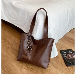 Vue détaillée du sac cabas marron foncé avec étiquette en cuir et breloque tressée