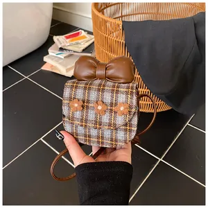 Detailed view of grey plaid mini bag with brown leather bow and floral accents